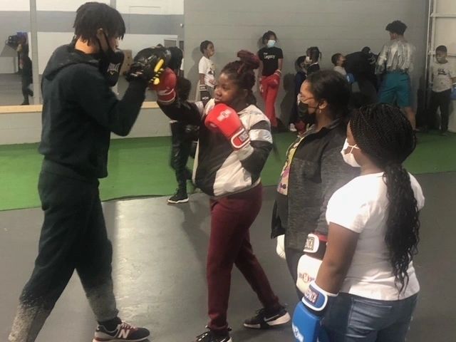 Members working the mitts with a coach during a group class